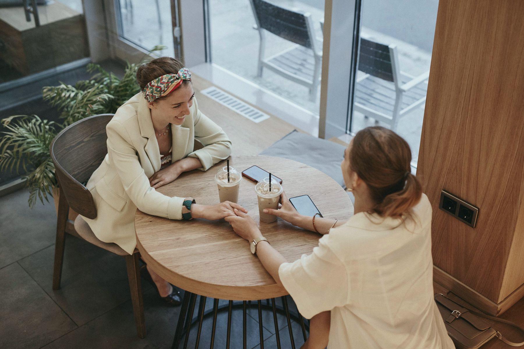 Two women talking across a small wooden table
