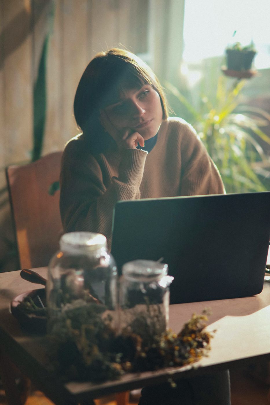 A woman at home on a video call, with plants on the windowsill